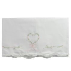 a white table cloth with pink and green embroidered hearts on it, along with a bow