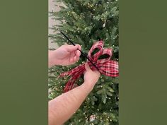 a person is tying a bow on a christmas tree