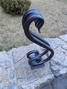 a metal sculpture sitting on top of a stone wall