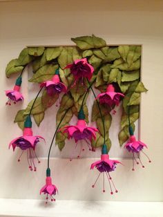 pink and green flowers are hanging on the wall