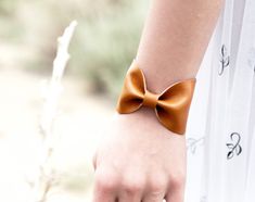 "Caramel Tan Bow Tie Vegan Leather Wide Cuff Bracelet by ForgottenCotton Because we know that Bow Ties are cool. Our beautiful Caramel Tan bow tie cuff is perfect 'oh so adorable' accessory. Dressed up or down, it is versatile, cute, and sure to get tons of compliments. Why we love it: Our cuffs are made to be versatile. You can wear our cuffs on either your wrist or your scarf (or both!) We chose high quality vegan leather that has the look and feel of leather without the guilt. Hand stitched t Elegant Brown Cuff Bracelet Gift, Elegant Brown Cuff Bracelet As Gift, Brown Bracelet Wristlet As Gift, Brown Leather Bracelet For Party, Adjustable Brown Bracelets For Party, Tan Bow Tie, Wrist Tattoo Cover Up, Scarf Cuff, Leather Scarf