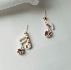 two pairs of white and pink earrings with flowers on the bottom, one is gold