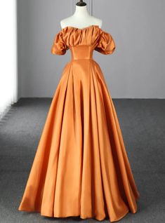 Aspire to stand out with this captivating orange prom dress, designed to make a bold statement. The off-shoulder neckline features intricately ruched fabric that adds texture and depth to the bodice, creating a visually stunning effect. The puffy sleeves provide a touch of vintage charm while ensuring you remain the center of attention. The fitted waist accentuates your figure before cascading into a full, floor-length skirt that moves gracefully with every step. Made from high-quality satin, this gown offers a luxurious sheen that reflects light beautifully, enhancing its vibrant color. The dress is both elegant and comfortable, ensuring you feel confident and at ease throughout the night. Perfect for those who dare to be different, this prom dress is a blend of classic elegance and moder Prom Dress Off The Shoulder, Orange Floor, Orange Outfits, Simple Evening Dress, Prom Dresses Off The Shoulder, Orange Prom Dresses, Simple Prom Dress Long, Formal Prom Dresses Long, Orange Satin