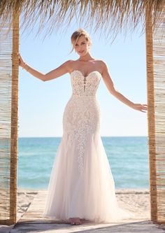 a woman in a wedding dress standing on the beach