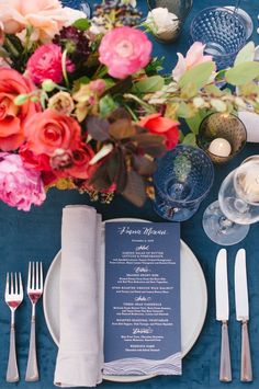 a table set with silverware, flowers and menus for an elegant wedding reception