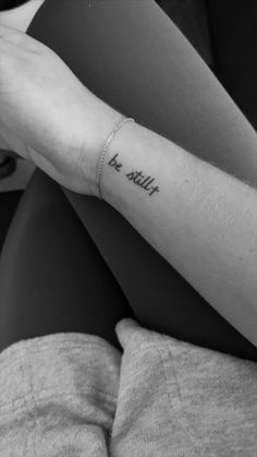 a woman's arm with the word be still tattooed on it, in black and white