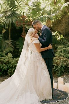 a bride and groom embracing each other in front of some palm trees at their wedding