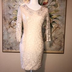 Nwt Never Worn, Size Small, 92% Nylon 8% Spandex Stretch Ivory Lace Dress, Fully Lined With An Ivory Stretch Jersey Like Fabric, Trendy Statement Doily Lace Collar With Pearls, And Rhinestones. Open Oval Back Wtih 2 Pearls And Loops Closure At The Top. Back Zipper Easy To Put On. Dress Hits Above The Knee. Retail: $80 Armpit To Armpit: 17” Sleeve Length From Top Shoulder: 18.5” Length From Back Shoulder: 30.5” Waist Laying Flat: 15” **New To Poshmark Use My Referral Code Michelemc_2021 On Your F Spring Wedding Stretch Bodycon Dress, Cream Bodycon Mini Dress For Party, Elegant Cream Lace Mini Dress, Chic Cream Stretch Dress, Cream Fitted Bodycon Party Dress, Cream Fitted Bodycon Dress For Party, Elegant White Stretch Lace Dress, White Glamorous Bodycon Dress, Glamorous White Bodycon Dress