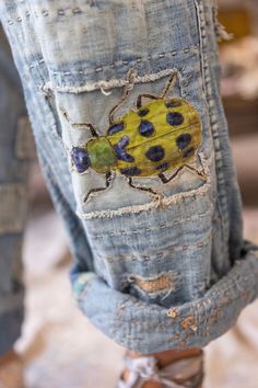 a lady bug painted on the back of someone's jean pants with holes in it