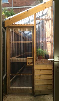 an open door to a small building with plants in the back ground and on top of it