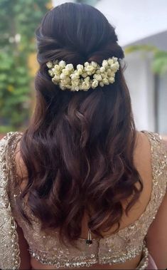 the back of a woman's head with flowers in her hair, wearing a gold dress