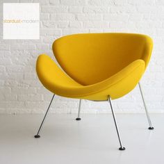 a yellow chair sitting in front of a white brick wall