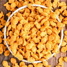 a white bowl filled with cheetos sitting on top of a wooden table