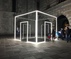 people are standing around in an open space with lights on the sides and inside it