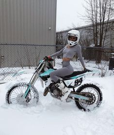 a woman sitting on top of a dirt bike in the snow