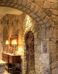 a bathroom with stone walls and an arched doorway that leads to a sink area in the corner