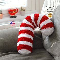 there is a red and white striped knitted pillow on the back of a couch