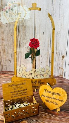 a wooden box with a rose in it and two other boxes next to it on a table