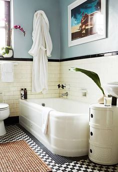 a white bath tub sitting next to a window in a bathroom with black and white checkered flooring