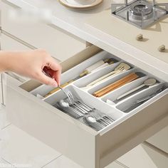 a person is opening the drawer with their utensils