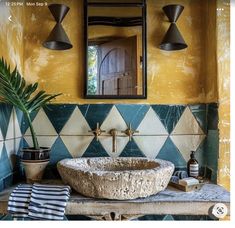 a bathroom sink sitting under a mirror next to a potted plant