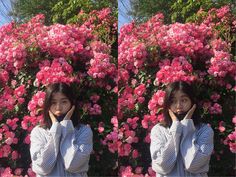 a woman standing in front of pink flowers while talking on her cell phone with both hands