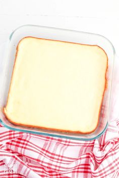 a casserole dish with cheese in it on a red and white checkered cloth