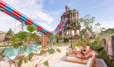 people sitting on lounge chairs in front of a water slide