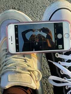 a person taking a selfie with their cell phone while standing on the pavement in front of them