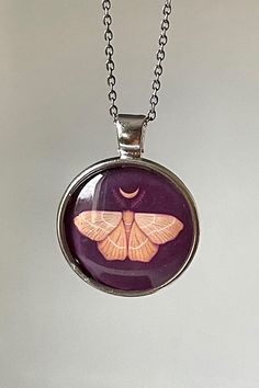 Round metal cabochon necklace with stainless steel chain and original art of moth and moon in orange and purple Sterling Silver Butterfly Necklace, Purple Moon Phase Necklace For Gifts, Witchy Butterfly, Handmade Spiritual Butterfly Necklace, Moth Necklace, Cottagecore Gifts, Cabochon Necklace, Butterfly Pendant Necklace, Witchy Jewelry