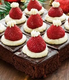 chocolate cake with strawberries on top and white frosting in the shape of santa hats