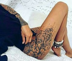 a woman laying on top of a bed next to a white sheet covered in tattoos