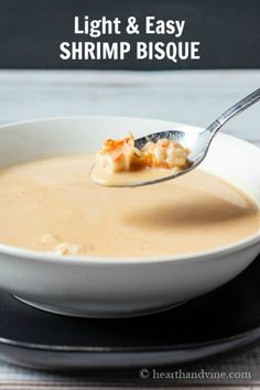 a white bowl filled with soup on top of a black and white saucer next to a silver spoon