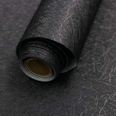 a roll of black leather on top of a gray surface with the end rolled up