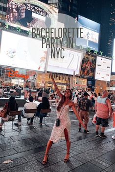 a woman holding up a sign in the middle of a crowded city street at night