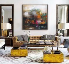 a living room filled with lots of furniture next to two lamps and paintings on the wall