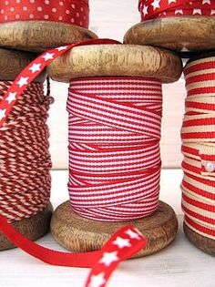 several spools of red and white twine on wooden spools with stars