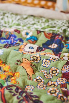 a close up view of a bed with colorful bedspread and flowers on it