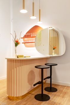 two stools in front of a counter with a mirror on the wall behind it