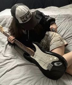 a person laying on top of a bed with a guitar in front of their face