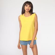 "Vintage 70s tank top in yellow. Sleeveless with a round neckline. Rear zipper. Note: The colour is blowing out a bit, it's not as bright in person. Every garment we sell is authentic vintage and one-of-a-kind! You will receive the exact item photographed. Condition: Very good vintage. Best fits women's: Small Material: Polyester MEASUREMENTS Taken from seam to seam while the garment is lying flat. Double the armpit, waist, and hips For reference, model is 5'10\" and measures 32-23-34. Length fr Retro Spring Tank Top, Retro Crew Neck Tank Top For Summer, Retro Spring Vest Tank Top, Retro Vest Tank Top For Spring, Retro Yellow Tank Top For Spring, Yellow Retro Sleeveless Tank Top, Retro Yellow Sleeveless Tank Top, Retro Sleeveless Vest Top, Casual Yellow Tank Vest