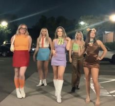 four women in short skirts are standing on the street