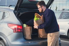 a man loading his groceries into the back of a car