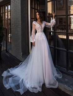 a woman in a white wedding dress standing on a wooden floor next to a building