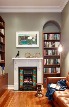 a living room filled with furniture and a fire place in front of a book shelf