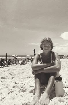 a woman sitting on top of a sandy beach