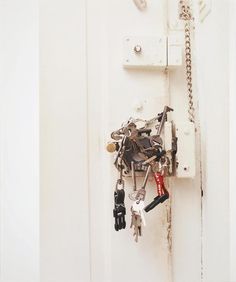 a bunch of keys are hanging on a door handle with chains and locks attached to it