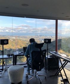 a man sitting at a desk in front of a window looking out on the city