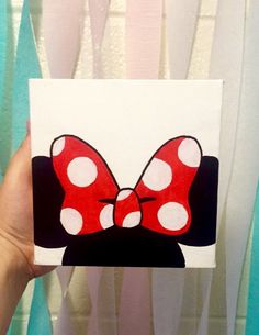 a hand holding up a card with a minnie mouse bow on it's head