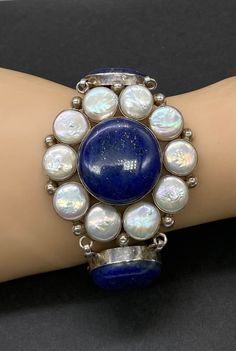 "Beautiful Vintage Stamped 925 Sterling Silver Art Deco with Genuine Huge Blue Lapis Lazuli and Freshwater Coin Pearl Flower Large Bracelet Good Pre/owned Condition Measures 8 1/8\" length toggle clasp adjustable by 2 1/8\" width." Artisan Blue Sterling Silver Bracelet, Artisan Blue Sterling Silver Bracelets, Artisan Adjustable Blue Sterling Silver Bracelet, Adjustable Blue Sterling Silver Bracelet, Handmade Elegant Blue Sterling Silver Bracelet, Blue Sterling Silver Round Bracelet, Blue Sterling Silver Bracelet, Blue Round Sterling Silver Bracelet, Formal Blue Bracelets With Cabochon